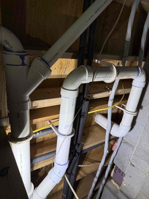 Completed bathroom drain repipe installation in crawl space and attic areas. Removed existing deteriorated drain lines and installed new white PVC drainage system with proper venting throughout the affected zones. Routed multiple drain lines through wooden framing members, securing pipes according to code requirements with appropriate hangers and supports. Installed various fittings including elbows, tees, and connectors to create functional drainage network. Applied primer and solvent cement to all PVC connections to ensure watertight, permanent joints. Coordinated pipe runs with existing structural elements including floor joists, studs, and foundation walls. Added black foam insulation to designated pipe sections for condensation control and noise reduction. Verified proper slope on all horizontal drain runs to ensure adequate drainage flow. System tested and confirmed operational with no leaks detected at any connection points. Completed bathroom drain repipe installation in crawl space and attic areas. Removed existing deteriorated drain lines and installed new white PVC drainage system with proper venting throughout the affected zones. Routed multiple drain lines through wooden framing members, securing pipes according to code requirements with appropriate hangers and supports. Installed various fittings including elbows, tees, and connectors to create functional drainage network. Applied primer and solvent cement to all PVC connections to ensure watertight, permanent joints. Coordinated pipe runs with existing structural elements including floor joists, studs, and foundation walls. Added black foam insulation to designated pipe sections for condensation control and noise reduction. Verified proper slope on all horizontal drain runs to ensure adequate drainage flow. System tested and confirmed operational with no leaks detected at any connection points.