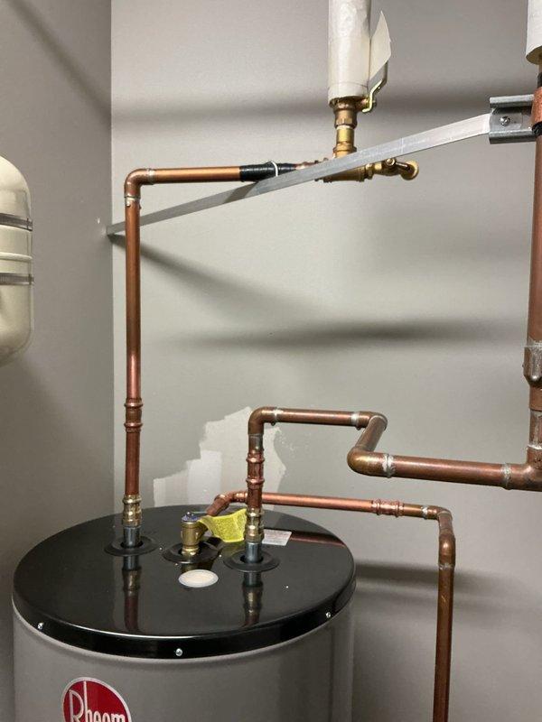 Completed installation of Rheem residential water heater system with all required plumbing connections and safety components. Installed expansion tank with proper mounting brackets and brass fittings, connected copper supply and distribution lines with appropriate shutoff valves, and integrated PVC venting system. All connections were properly secured, tested for leaks, and verified operational per manufacturer specifications. Completed installation of Rheem residential water heater system with all required plumbing connections and safety components. Installed expansion tank with proper mounting brackets and brass fittings, connected copper supply and distribution lines with appropriate shutoff valves, and integrated PVC venting system. All connections were properly secured, tested for leaks, and verified operational per manufacturer specifications.