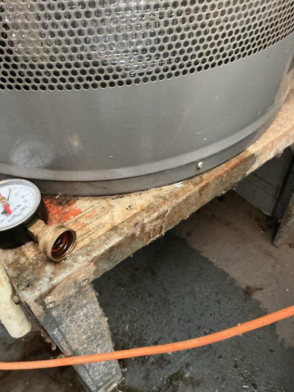 Responded to service call for water heater leaking at base. Upon inspection, found significant corrosion and rust damage to the water heater tank and surrounding support structure. The unit, manufactured in October 2017, exhibited deterioration at the base with visible moisture damage extending to the wooden support beam beneath the appliance. Documented equipment condition with photographs showing specification labels, safety warnings, and extent of corrosion damage affecting both the tank and mounting platform. The pressure relief valve assembly and associated brass fittings were inspected and photographed. Concrete floor showed evidence of water exposure from the leak. Customer was advised of findings and provided with photographic documentation of the water heater's condition for review and determination of next steps for repair or replacement. Responded to service call for water heater leaking at base. Upon inspection, found significant corrosion and rust damage to the water heater tank and surrounding support structure. The unit, manufactured in October 2017, exhibited deterioration at the base with visible moisture damage extending to the wooden support beam beneath the appliance. Documented equipment condition with photographs showing specification labels, safety warnings, and extent of corrosion damage affecting both the tank and mounting platform. The pressure relief valve assembly and associated brass fittings were inspected and photographed. Concrete floor showed evidence of water exposure from the leak. Customer was advised of findings and provided with photographic documentation of the water heater's condition for review and determination of next steps for repair or replacement.