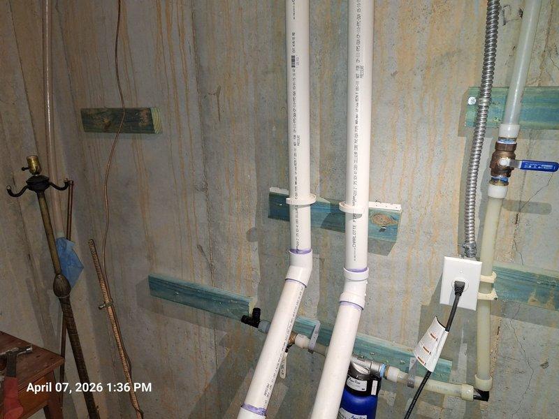 Responded to service call regarding no water flow at faucets following toilet usage and concerns about newly installed whole home filtration system lacking a bypass mechanism. Inspected plumbing system in utility area, including exposed PVC drainage and venting lines, copper supply piping with brass valve assembly, and blue cylindrical water filtration device mounted in wall cavity. Verified proper installation and mounting of filtration system components using appropriate brackets and supports. Tested water flow throughout system to diagnose pressure issues affecting fixture operation. Confirmed filtration unit operational status and addressed customer concerns regarding absence of bypass configuration on current installation. Responded to service call regarding no water flow at faucets following toilet usage and concerns about newly installed whole home filtration system lacking a bypass mechanism. Inspected plumbing system in utility area, including exposed PVC drainage and venting lines, copper supply piping with brass valve assembly, and blue cylindrical water filtration device mounted in wall cavity. Verified proper installation and mounting of filtration system components using appropriate brackets and supports. Tested water flow throughout system to diagnose pressure issues affecting fixture operation. Confirmed filtration unit operational status and addressed customer concerns regarding absence of bypass configuration on current installation.