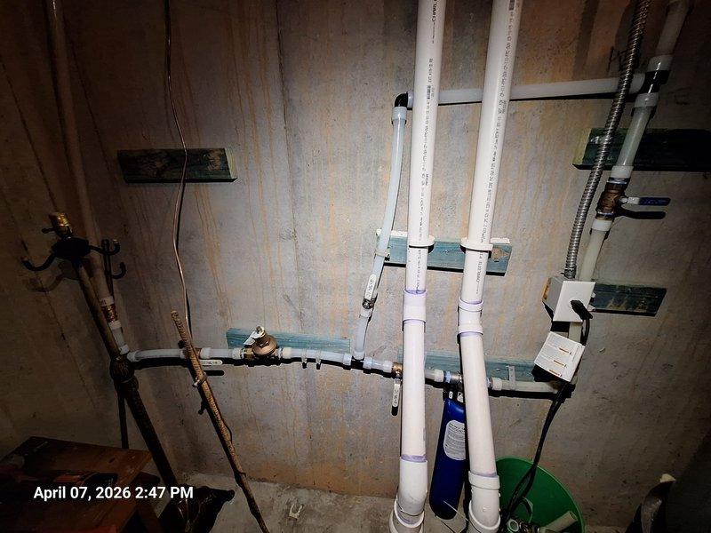 Responded to service call regarding no water flow at faucets following toilet usage and concerns about newly installed whole home filtration system lacking a bypass mechanism. Inspected plumbing system in utility area, including exposed PVC drainage and venting lines, copper supply piping with brass valve assembly, and blue cylindrical water filtration device mounted in wall cavity. Verified proper installation and mounting of filtration system components using appropriate brackets and supports. Tested water flow throughout system to diagnose pressure issues affecting fixture operation. Confirmed filtration unit operational status and addressed customer concerns regarding absence of bypass configuration on current installation. Responded to service call regarding no water flow at faucets following toilet usage and concerns about newly installed whole home filtration system lacking a bypass mechanism. Inspected plumbing system in utility area, including exposed PVC drainage and venting lines, copper supply piping with brass valve assembly, and blue cylindrical water filtration device mounted in wall cavity. Verified proper installation and mounting of filtration system components using appropriate brackets and supports. Tested water flow throughout system to diagnose pressure issues affecting fixture operation. Confirmed filtration unit operational status and addressed customer concerns regarding absence of bypass configuration on current installation.