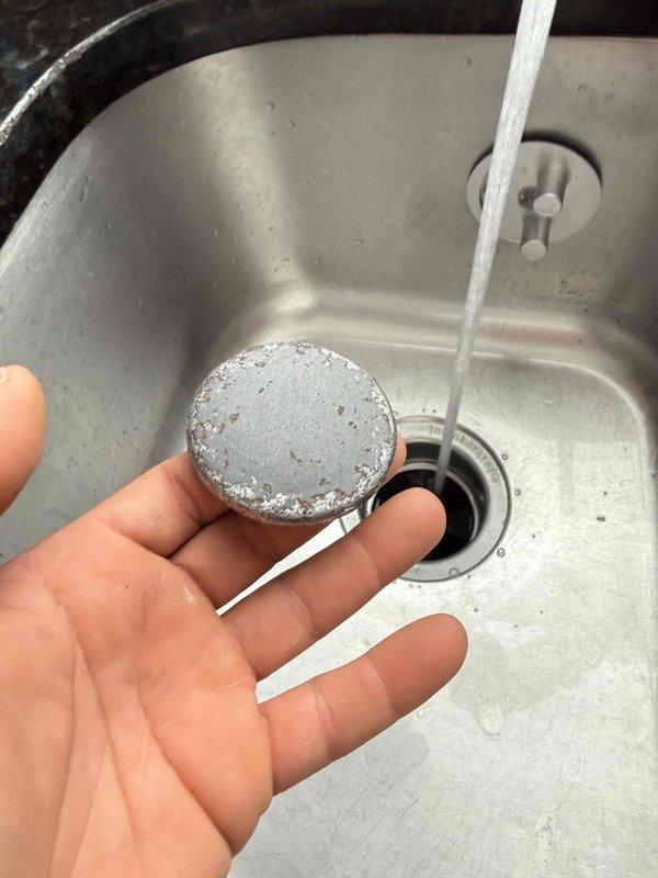 Responded to service call for non-functioning garbage disposal and continuously running toilet. Inspected kitchen sink drain system and removed heavily corroded disposal stopper and drain cover components showing significant mineral buildup from hard water exposure. Documented existing conditions with photographs showing extent of corrosion and component deterioration. Assessed garbage disposal unit for operational issues and identified failed internal mechanisms requiring replacement parts or unit replacement.