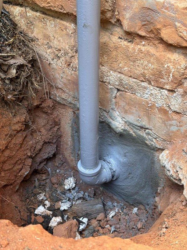 Completed gas line repair involving excavation and access to underground piping system. Repaired compromised gas line connection at elbow joint located beneath grade level in clay soil conditions. Sealed pipe penetration through concrete block foundation wall using expanding foam to ensure proper weatherproofing and prevent air infiltration. Documented existing conditions showing PVC conduit installation and underground junction point with standing water present at base of excavation. Completed gas line repair involving excavation and access to underground piping system. Repaired compromised gas line connection at elbow joint located beneath grade level in clay soil conditions. Sealed pipe penetration through concrete block foundation wall using expanding foam to ensure proper weatherproofing and prevent air infiltration. Documented existing conditions showing PVC conduit installation and underground junction point with standing water present at base of excavation.