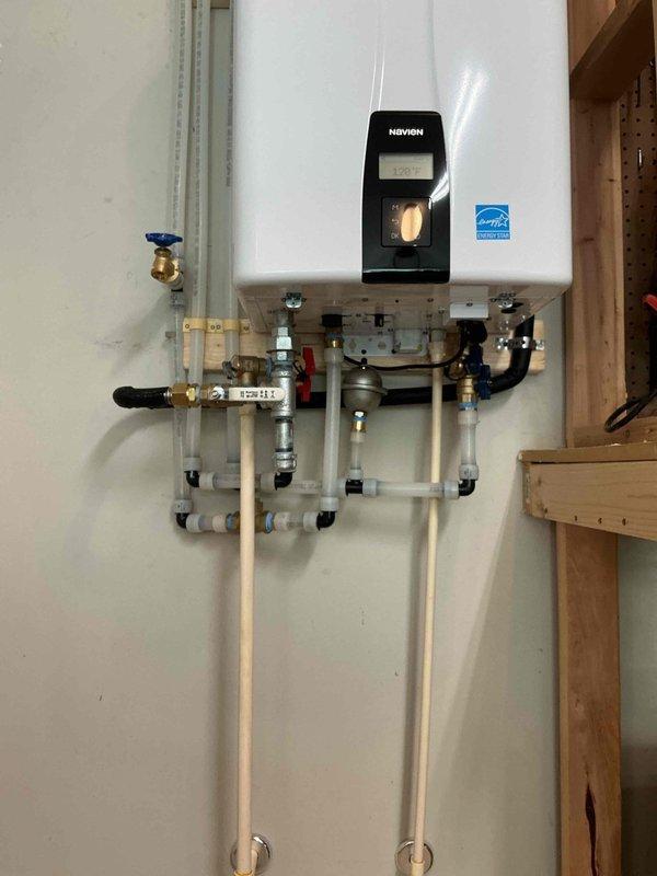 Completed installation of Navien tankless water heater system with full plumbing integration. Mounted unit to interior wall with proper venting using PVC exhaust piping, installed comprehensive valve manifold assembly with pressure gauges and isolation valves, and connected all hot and cold water supply lines using combination of copper, PEX, and flexible connectors with blue-handled shutoff valves for system control. Completed installation of Navien tankless water heater system with full plumbing integration. Mounted unit to interior wall with proper venting using PVC exhaust piping, installed comprehensive valve manifold assembly with pressure gauges and isolation valves, and connected all hot and cold water supply lines using combination of copper, PEX, and flexible connectors with blue-handled shutoff valves for system control.