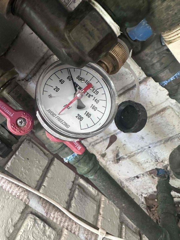 Responded to service call regarding unusual noise emanating from wall during washing machine operation. Upon arrival, inspected LG ThinQ front-loading washing machine and surrounding laundry area. Documented appliance condition and installation setup, noting machine positioned on white platform base with control panel displaying normal operational indicators.
Investigated potential noise sources by examining water supply connections and pressure regulation system. Inspected pressure gauge assembly showing readings within normal operating range (0-200 scale), connected red ball valve, and associated copper and brass threaded piping. Evaluated flexible hose connections and mechanical components for signs of water hammer, loose fittings, or vibration transmission to wall structure. Photographed plumbing infrastructure including gauge assembly, valve connections, and pipe routing to document current installation configuration for further assessment if needed. Responded to service call regarding unusual noise emanating from wall during washing machine operation. Upon arrival, inspected LG ThinQ front-loading washing machine and surrounding laundry area. Documented appliance condition and installation setup, noting machine positioned on white platform base with control panel displaying normal operational indicators.
Investigated potential noise sources by examining water supply connections and pressure regulation system. Inspected pressure gauge assembly showing readings within normal operating range (0-200 scale), connected red ball valve, and associated copper and brass threaded piping. Evaluated flexible hose connections and mechanical components for signs of water hammer, loose fittings, or vibration transmission to wall structure. Photographed plumbing infrastructure including gauge assembly, valve connections, and pipe routing to document current installation configuration for further assessment if needed.