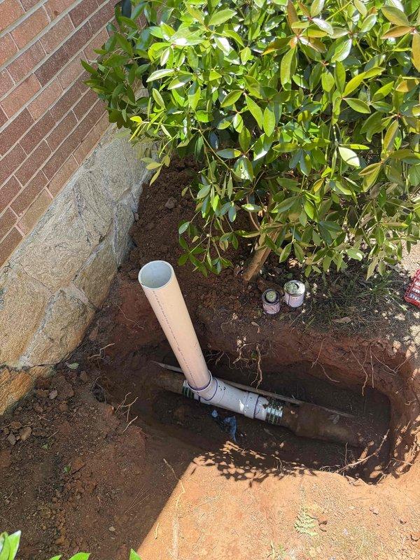 Excavated trench and installed new PVC cleanout access point with proper fittings and capped termination. Completed installation in landscaped area adjacent to building foundation, ensuring proper depth and accessibility while working around existing decorative rock borders and vegetation. Excavated trench and installed new PVC cleanout access point with proper fittings and capped termination. Completed installation in landscaped area adjacent to building foundation, ensuring proper depth and accessibility while working around existing decorative rock borders and vegetation.