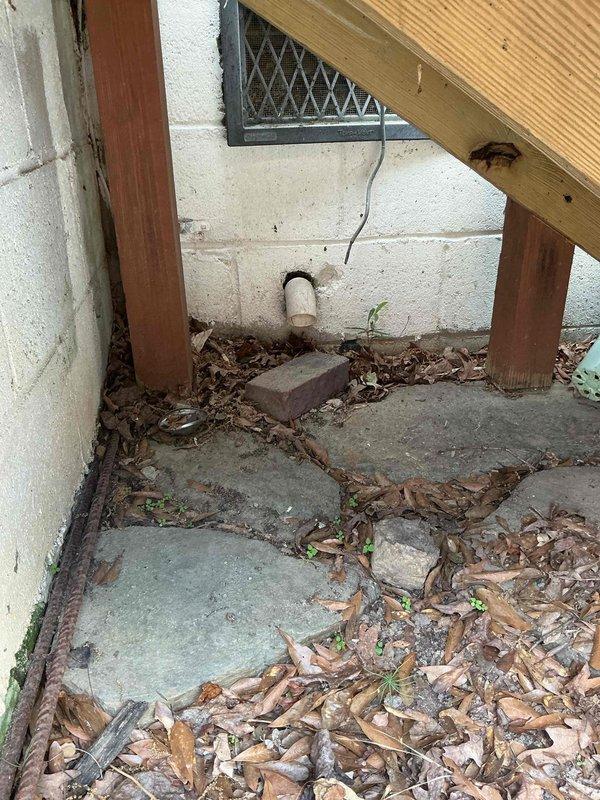 Responded to service call for sump pump inspection with concerns regarding discharge piping functionality. Upon arrival, evaluated exterior discharge line termination point at foundation wall and confirmed proper outlet configuration through foundation vent area. Inspected interior sump basin installation, including vertical discharge pipe with floor penetration boot assembly. Observed evidence of previous moisture infiltration around pipe penetration point based on staining patterns on protective floor sheeting. Verified discharge pipe routing, connections, and mechanical systems integration. Documented current system condition with photographic evidence for service records. Responded to service call for sump pump inspection with concerns regarding discharge piping functionality. Upon arrival, evaluated exterior discharge line termination point at foundation wall and confirmed proper outlet configuration through foundation vent area. Inspected interior sump basin installation, including vertical discharge pipe with floor penetration boot assembly. Observed evidence of previous moisture infiltration around pipe penetration point based on staining patterns on protective floor sheeting. Verified discharge pipe routing, connections, and mechanical systems integration. Documented current system condition with photographic evidence for service records.