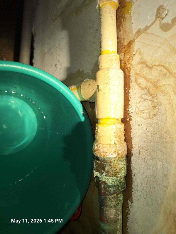 Responded to service call for leaking water heater in basement utility area. Upon inspection, identified active water leak originating from corroded connection points on aging copper supply lines. The existing plumbing infrastructure showed significant deterioration with heavy oxidation and greenish patina on copper piping, along with evidence of previous moisture intrusion on surrounding walls. Assessed transition points between newer yellow plastic piping and older metal sections, which exhibited compromised integrity. Isolated water supply to prevent further leakage and water damage. Documented extensive corrosion on horizontal pipe assembly and deteriorated connections requiring replacement. Noted compromised plumbing components with visible corrosion, tape repairs, and oxidized surfaces indicating end of service life. Recommended complete replacement of corroded copper sections and upgrading connection points to prevent future failures. Responded to service call for leaking water heater in basement utility area. Upon inspection, identified active water leak originating from corroded connection points on aging copper supply lines. The existing plumbing infrastructure showed significant deterioration with heavy oxidation and greenish patina on copper piping, along with evidence of previous moisture intrusion on surrounding walls. Assessed transition points between newer yellow plastic piping and older metal sections, which exhibited compromised integrity. Isolated water supply to prevent further leakage and water damage. Documented extensive corrosion on horizontal pipe assembly and deteriorated connections requiring replacement. Noted compromised plumbing components with visible corrosion, tape repairs, and oxidized surfaces indicating end of service life. Recommended complete replacement of corroded copper sections and upgrading connection points to prevent future failures.
