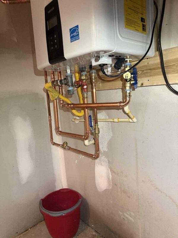 Completed tankless water heater replacement with full system integration. Removed existing unit and installed new Energy Star certified tankless water heater with comprehensive copper piping network, brass fittings, and multiple shut-off valves with blue handles for isolation capability. Integrated yellow flexible gas lines into the plumbing configuration, established electrical connections, and verified proper pressure readings on system gauge. All connections tested and operational. Completed tankless water heater replacement with full system integration. Removed existing unit and installed new Energy Star certified tankless water heater with comprehensive copper piping network, brass fittings, and multiple shut-off valves with blue handles for isolation capability. Integrated yellow flexible gas lines into the plumbing configuration, established electrical connections, and verified proper pressure readings on system gauge. All connections tested and operational.