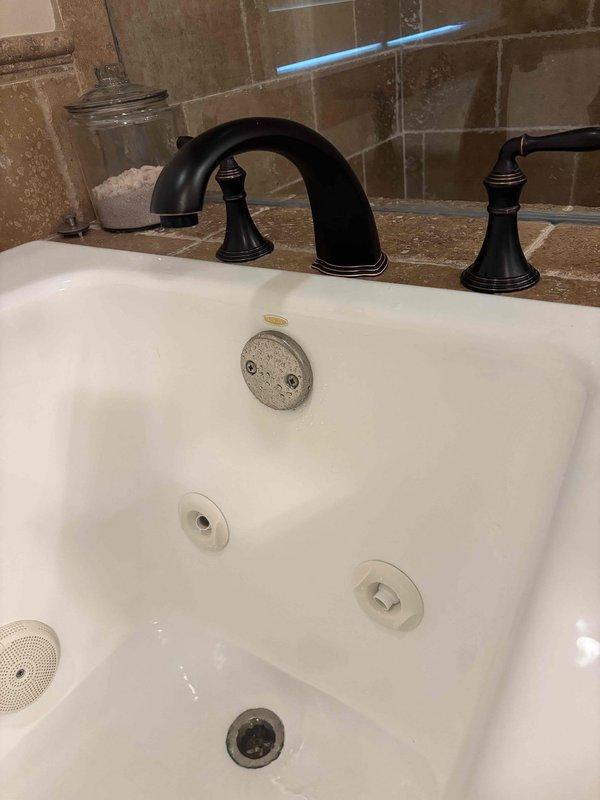 Responded to reported ceiling leak and traced source to bathroom plumbing above affected area. Upon investigation, identified leaking jet tub drain assembly allowing water to seep through floor joists into ceiling below. Documented existing water staining on subfloor and structural members surrounding white PVC drain piping. Tightened drain connections and inspected all jet tub plumbing fixtures for proper sealing to prevent further water intrusion and damage to ceiling below. Responded to reported ceiling leak and traced source to bathroom plumbing above affected area. Upon investigation, identified leaking jet tub drain assembly allowing water to seep through floor joists into ceiling below. Documented existing water staining on subfloor and structural members surrounding white PVC drain piping. Tightened drain connections and inspected all jet tub plumbing fixtures for proper sealing to prevent further water intrusion and damage to ceiling below.