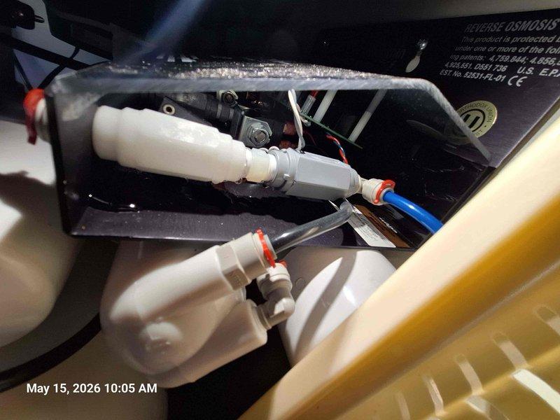 Responded to follow-up service call for leak in Aquathin reverse osmosis system installed previous day. Inspected undersink installation and identified leak source at connection points. Examined white plastic tubing connections at horizontal pipe assembly with red and orange clips, verified proper seating of all quick-connect fittings. Checked blue component connections and black plastic fittings for secure attachment. Tightened connections at metallic valve assembly where tubing routes to drain, storage tank, and feed lines. Verified IQ-EMP electronic memory panel indicators showing normal operation with system power and appropriate status lights illuminated. Tested system operation through complete cycle, confirmed no leaks present at all connection points. System functioning properly with no further issues detected. Responded to follow-up service call for leak in Aquathin reverse osmosis system installed previous day. Inspected undersink installation and identified leak source at connection points. Examined white plastic tubing connections at horizontal pipe assembly with red and orange clips, verified proper seating of all quick-connect fittings. Checked blue component connections and black plastic fittings for secure attachment. Tightened connections at metallic valve assembly where tubing routes to drain, storage tank, and feed lines. Verified IQ-EMP electronic memory panel indicators showing normal operation with system power and appropriate status lights illuminated. Tested system operation through complete cycle, confirmed no leaks present at all connection points. System functioning properly with no further issues detected.