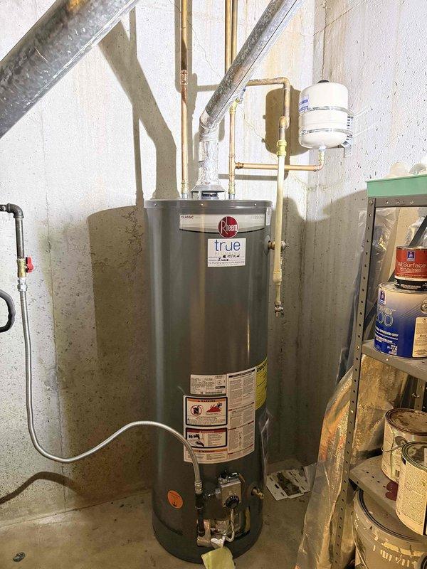 Responded to service call for leaking gas water heater. Upon inspection, identified active leak at gas supply connection point on Rheem residential water heater unit. Shut off gas supply using existing blue-handled ball valve, disconnected compromised gas line fittings, and replaced failed components with new brass connectors and proper pipe sealant rated for natural gas applications. Pressure tested all gas connections using approved leak detection solution to verify system integrity. Restored gas supply, cycled unit through startup sequence, and confirmed proper ignition and operation with no detectable leaks. Inspected associated plumbing connections including copper water lines, expansion tank mounting, and pressure relief valve for any additional issues requiring attention.