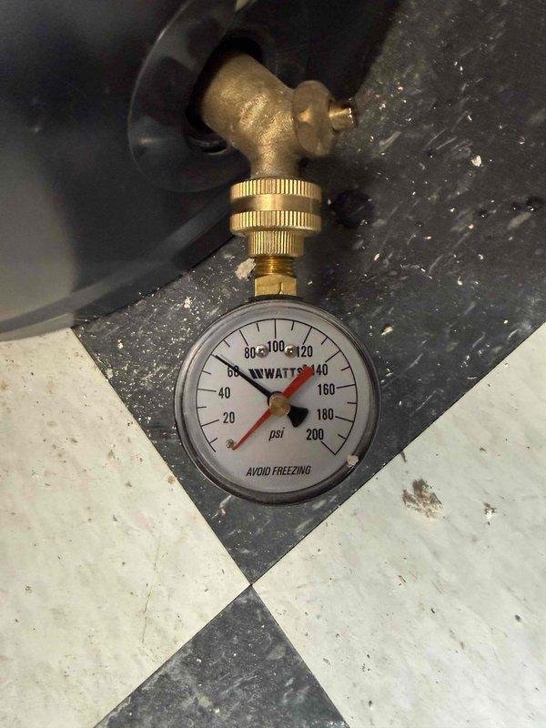 Corrected water fountain plumbing connection that was improperly hooked up to the hot water supply line. Reconnected fountain to the cold water system, installed pressure regulation equipment with WATTS gauge reading 0-200 PSI, and verified proper copper pipe connections with appropriate fittings and shutoff valve. Documented installation with pressure gauge assembly and piping configuration to ensure compliance with plumbing standards for potable water fixtures.