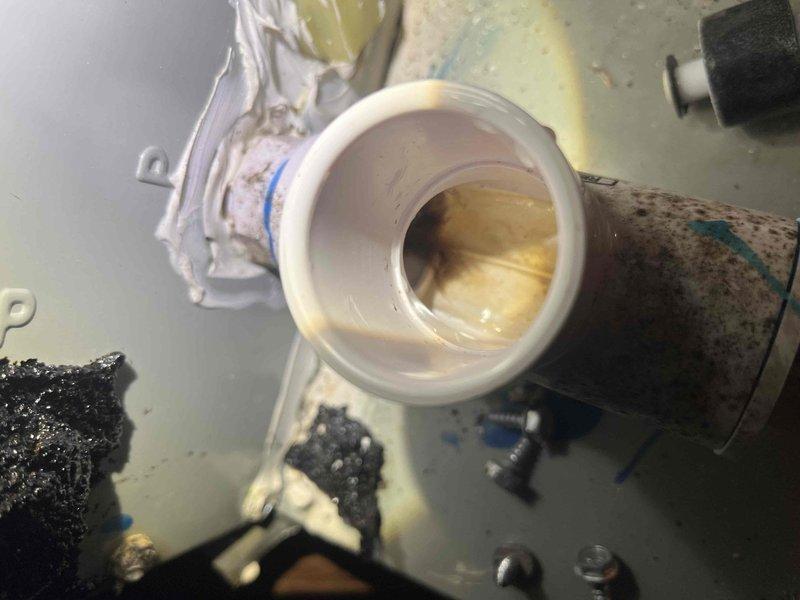 Responded to service call for leaking condensate drain line. Upon inspection, found PVC condensate piping with significant interior staining and buildup causing drainage issues. Documented existing condition showing brownish-yellow discoloration inside pipe fittings and residue accumulation on exterior surfaces. Inspected drain line connections, trap assembly, and termination point. System components showed signs of age and required maintenance to restore proper condensate flow and prevent future water damage.