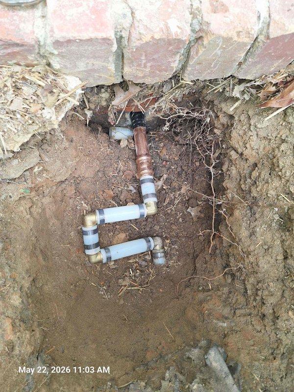 Responded to customer report of water pooling in yard with additional leaking shower head and toilet shut-off valve. Investigated attic space and located copper waterline connections above insulation. Excavated yard area where previous waterline repair was performed and exposed compromised PVC plumbing configuration with multiple elbow fittings showing signs of failure in sandy soil conditions. Documented both attic plumbing infrastructure and underground pipe damage with photographic evidence for repair assessment.