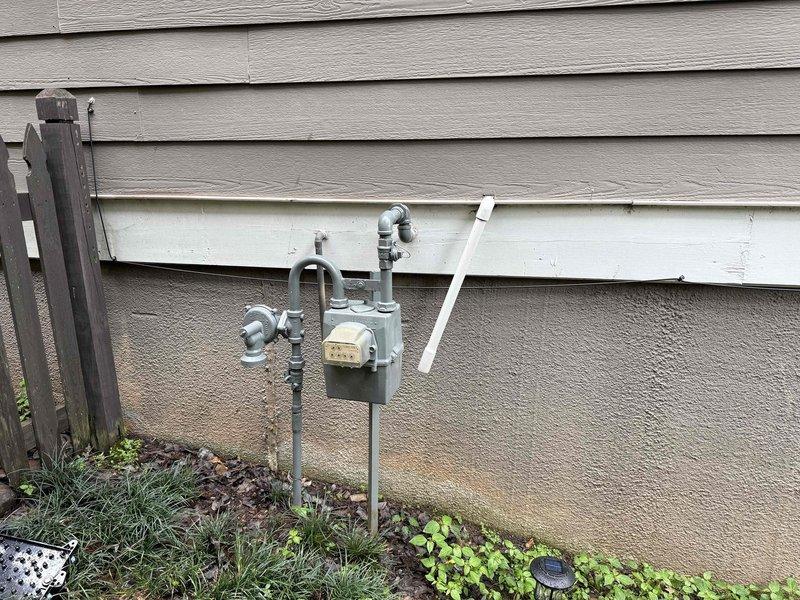 Completed standard water heater service call at residential property. Performed inspection of white cylindrical storage-type water heater located in basement alongside HVAC equipment. Verified proper operation of unit, examined connections including copper supply lines and PVC venting system, and confirmed all safety labels and warnings were intact. Inspected external gas meter assembly and associated piping on building exterior to ensure proper gas supply to appliances. All components found to be functioning within normal parameters.