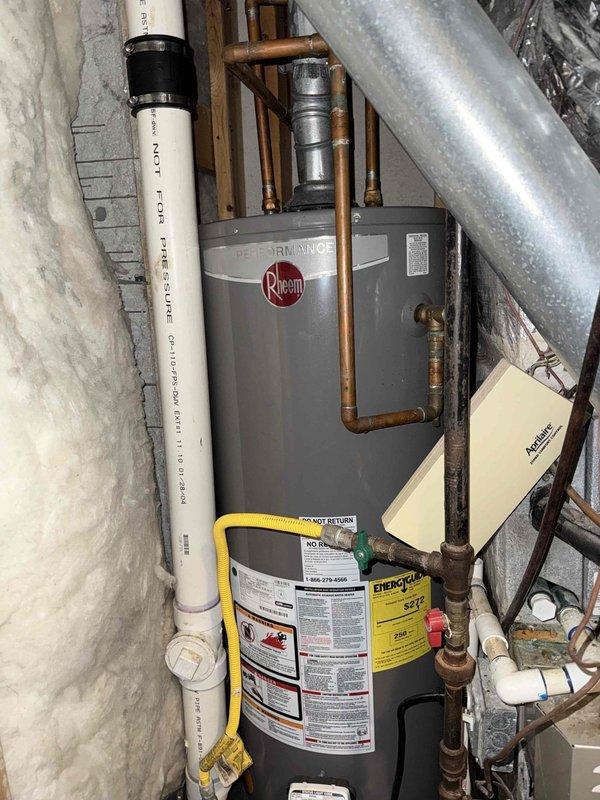 Completed standard water heater service call at residential property. Performed inspection of white cylindrical storage-type water heater located in basement alongside HVAC equipment. Verified proper operation of unit, examined connections including copper supply lines and PVC venting system, and confirmed all safety labels and warnings were intact. Inspected external gas meter assembly and associated piping on building exterior to ensure proper gas supply to appliances. All components found to be functioning within normal parameters.