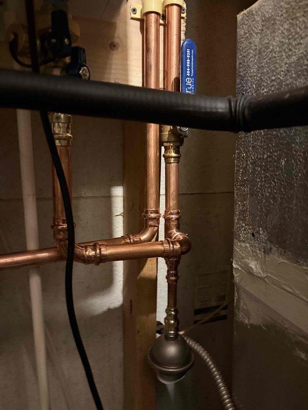 Completed tankless water heater installation in basement utility area. Installed new copper supply piping with multiple vertical runs and soldered connections, integrated PVC drainage and venting system, and mounted all components to exposed wall studs per manufacturer specifications. All piping connections tested and system fully operational.