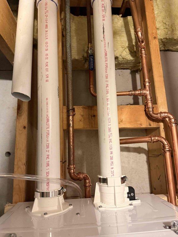 Completed tankless water heater installation in basement utility area. Installed new copper supply piping with multiple vertical runs and soldered connections, integrated PVC drainage and venting system, and mounted all components to exposed wall studs per manufacturer specifications. All piping connections tested and system fully operational.