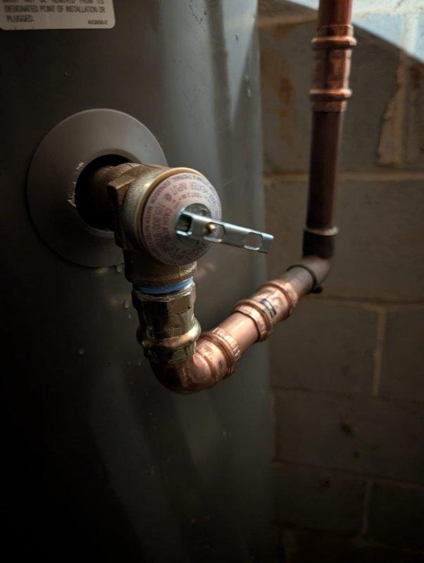 Responded to report of leaking temperature and pressure relief valve on water heater installed in 2023. Upon arrival, inspected the T&P valve assembly and associated copper piping for signs of active leakage or water damage. Documented existing plumbing configuration with photographs showing brass valve body, discharge piping, and surrounding area. No active leaking observed at time of inspection. Follow-up visit completed to assess condition and determine if replacement or further action required.