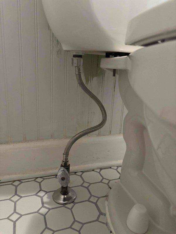 Responded to follow-up service call for reported toilet leak occurring after previous toilet removal and reinstallation during sewer scope procedure. Upon arrival, conducted thorough visual inspection of toilet installation, water supply connections, and surrounding floor area. Examined the flexible braided supply line connection from shut-off valve to tank inlet for proper seating and potential leakage points. Inspected wax ring seal and toilet base-to-floor connection for signs of water seepage. Verified all mounting bolts and hardware were properly secured following the previous reset. Documented conditions of white hexagonal tile flooring, beadboard wainscoting, and fixture connections with photographic evidence. No active leak observed during inspection visit.