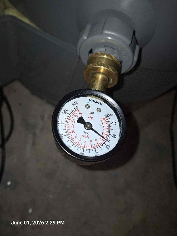 Responded to kitchen sink leak complaint. Upon inspection, identified leak originating from garbage disposal unit and associated drain connections beneath sink. Examined all plumbing components including black garbage disposal unit, white PVC P-trap assembly, and connection points. Checked system pressure using gauge to verify proper operation and rule out pressure-related issues. Tightened disposal mounting assembly and drain fittings to eliminate leak source. Tested system under running water conditions to confirm repair integrity and verify no additional moisture present.