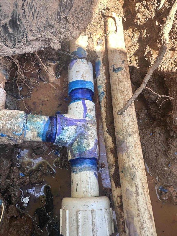 Responded to service call for significant water loss and wet area in yard. Located and excavated underground water line leak at PVC pipe fitting connection. Exposed damaged coupling and T-junction assembly showing signs of deterioration and age-related failure. Repaired compromised pipe connection to restore proper water flow and eliminate leak source.