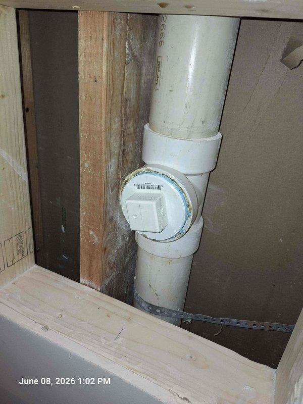 Responded to water leak complaint originating from main level shower with visible water intrusion through basement ceiling. Upon investigation, identified compromised plumbing connection at PVC drain assembly with evidence of active leaking and corrosion at pipe joint. Documented existing conditions showing rust staining and water damage at flange coupling. Inspected vertical drain line installation including cleanout fitting accessibility. Assessed structural framing for water damage and verified extent of moisture penetration. Photographed affected plumbing connections and surrounding areas to document pre-repair conditions and leak source location.