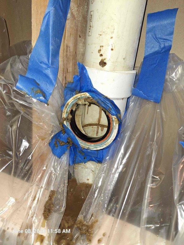 Responded to water leak complaint originating from main level shower with visible water intrusion through basement ceiling. Upon investigation, identified compromised plumbing connection at PVC drain assembly with evidence of active leaking and corrosion at pipe joint. Documented existing conditions showing rust staining and water damage at flange coupling. Inspected vertical drain line installation including cleanout fitting accessibility. Assessed structural framing for water damage and verified extent of moisture penetration. Photographed affected plumbing connections and surrounding areas to document pre-repair conditions and leak source location.