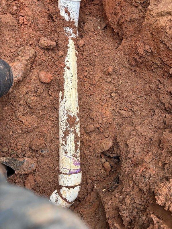 Completed sewer line replacement as specified in approved quote. Excavated trench through clay soil, removed deteriorated existing sewer pipe, and installed new white PVC sewer line with proper fittings and connections. All work performed to code specifications and site restored upon completion.