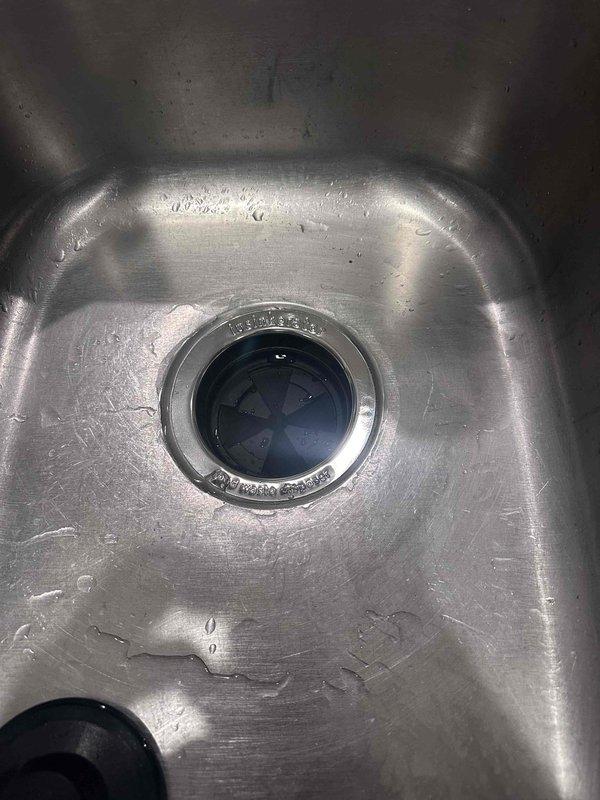 Responded to service call for leaking garbage disposal unit. Upon inspection, identified active leak from disposal housing and deteriorated mounting assembly. Documented existing water damage to cabinet floor and compromised plumbing connections. Photographed disposal unit, drain assembly, and affected areas for service records. Assessed condition of mounting flange, drain connections, and PVC trap configuration to determine repair requirements.