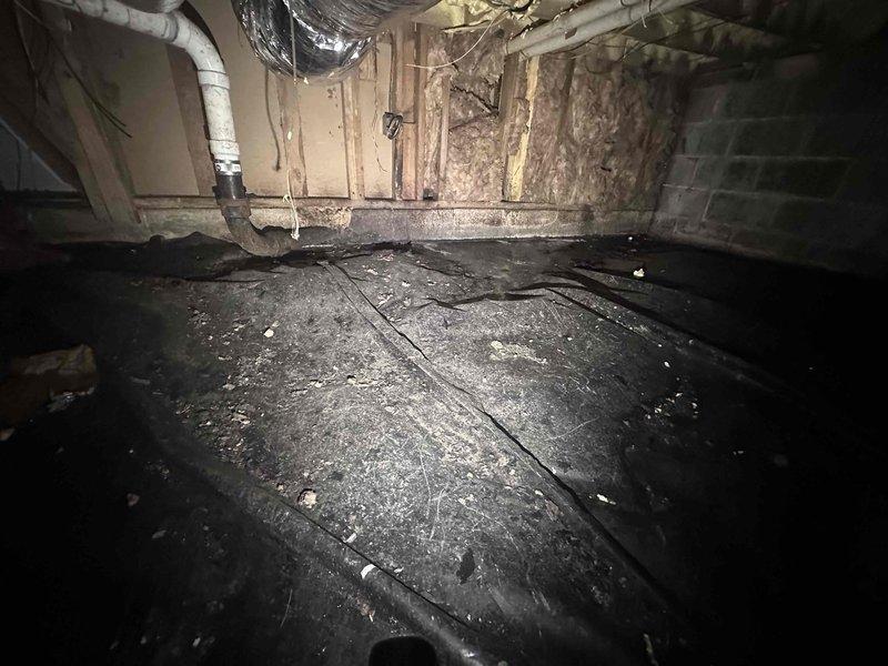 Responded to sewage leak in crawlspace and conducted thorough inspection of affected area. Upon arrival, accessed crawlspace and located corroded metal drain pipe with active leak contaminating the space. Documented existing conditions including severely deteriorated P-trap assembly with extensive rust and oxidation compromising pipe integrity. Photographed damaged plumbing components, contaminated soil beneath leak point, and surrounding structural elements for record purposes. Assessed crawlspace environment noting accumulated debris, dust-covered flooring, and exposed insulation materials in vicinity of leak. Identified compromised drainage system requiring replacement of corroded pipe section to resolve sewage discharge issue and prevent further contamination of crawlspace area.