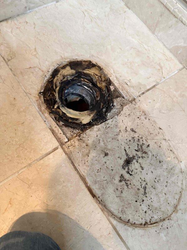 Performed sewer scope inspection of drainage system. Camera inspection revealed floor drain with significant deterioration, heavy black staining, and debris accumulation around drain opening indicating potential blockage or drainage issues. Documented conditions of accessible plumbing infrastructure including crawl space with exposed piping and electrical systems for maintenance records.