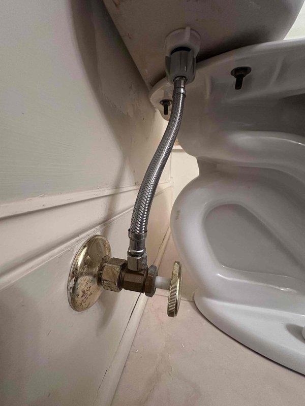 Responded to customer report of small leak at toilet shut-off valve. Upon inspection, identified leak originating from the chrome-plated angle stop valve connection point at the wall supply line. Evaluated braided stainless steel flexible supply line and threaded connections at both the tank inlet and shut-off valve. Tightened compression fittings at the valve to eliminate leak. Verified all connections were secure and tested system by cycling water supply on and off multiple times. Confirmed no active leaking present after repair and ensured proper water flow to toilet tank.