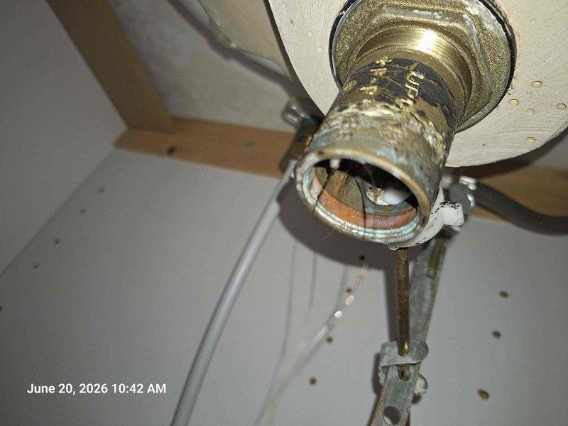 Responded to service call for leak under bathroom sink with possible obstruction in p-trap from dropped dental crown. Upon inspection, identified deteriorated flexible corrugated drain connector as source of leak. The white accordion-style flex pipe showed signs of wear at threaded connections. Documented existing plumbing configuration including P-trap assembly, black plastic piping, and metal mounting hardware. Also noted unrelated ceiling fixture above area displaying severe corrosion and water damage, indicating potential separate leak source requiring attention. Provided customer with documentation of findings and recommended replacement of compromised drain components and investigation of ceiling moisture issue.