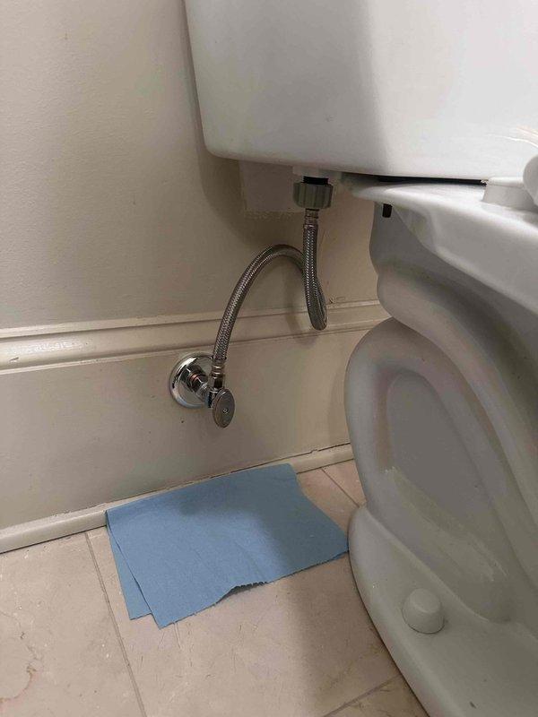 Replaced defective toilet stop valve with new chrome angle stop valve and installed new braided stainless steel flexible supply line. Verified proper water flow and tested for leaks to ensure reliable operation of wall-mounted toilet tank system.