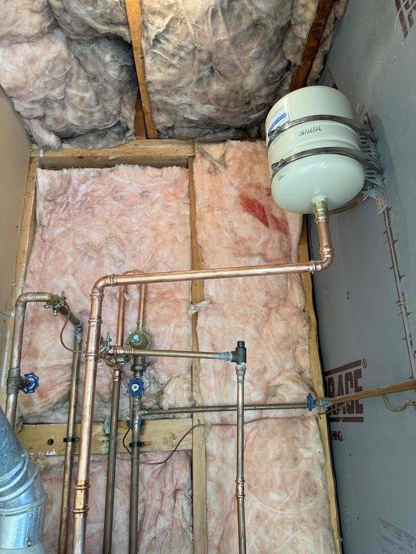 Completed thermal expansion tank rework and main shut-off valve installation in mechanical room. Reconfigured copper piping system with new ball valves for improved isolation and system control. Installed white expansion tank with secure mounting brackets to accommodate thermal expansion in the water heating system. All connections properly soldered and tested for leaks, with multiple shut-off points strategically placed throughout the piping network for future maintenance accessibility.