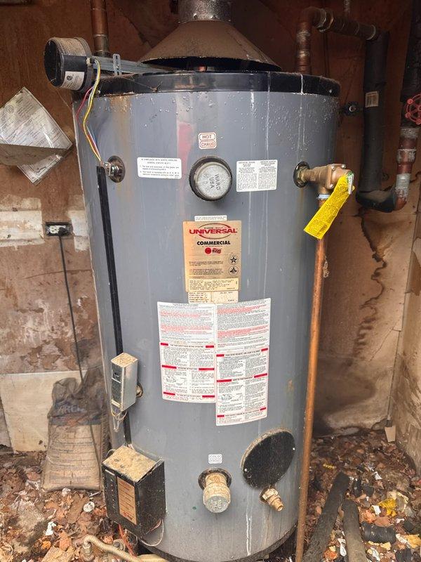 Responded to service call for leaking 100-gallon commercial gas water heater. Upon arrival, inspected Universal Commercial brand unit installed in basement utility area. Confirmed active leak condition and assessed overall system integrity. Documented existing installation showing water heater with standard plumbing connections including copper supply lines, pressure relief valve, and gas line connections. Unit displayed manufacturer specifications and safety labels on front face. Noted flue hood assembly at top of tank and electrical conduit connections on side of unit. Photographed complete installation for service records including all visible piping, valves, and component connections. Evaluated surrounding area conditions and documented workspace. Provided customer with photographic evidence of equipment condition and discussed findings regarding the compromised water heater requiring replacement due to tank failure. Responded to service call for leaking 100-gallon commercial gas water heater. Upon arrival, inspected Universal Commercial brand unit installed in basement utility area. Confirmed active leak condition and assessed overall system integrity. Documented existing installation showing water heater with standard plumbing connections including copper supply lines, pressure relief valve, and gas line connections. Unit displayed manufacturer specifications and safety labels on front face. Noted flue hood assembly at top of tank and electrical conduit connections on side of unit. Photographed complete installation for service records including all visible piping, valves, and component connections. Evaluated surrounding area conditions and documented workspace. Provided customer with photographic evidence of equipment condition and discussed findings regarding the compromised water heater requiring replacement due to tank failure.