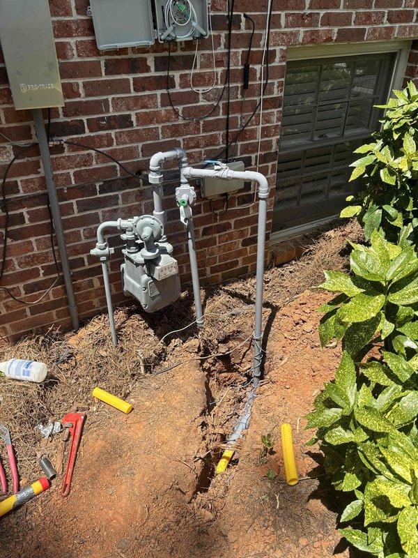 Completed installation of gas line extension to pool heater following utility locate clearance. Routed new gas piping from existing meter assembly on exterior brick wall, utilizing proper sizing and connections per code requirements. Installation included trenching through landscaped area adjacent to building, laying gas-rated pipe in prepared trench at proper depth, backfilling and compacting soil. All connections at gas meter tested for leaks using approved methods. Work area restored with disturbed soil graded and prepared for landscape replacement.