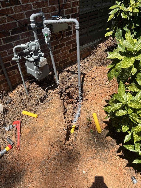 Completed installation of gas line extension to pool heater following utility locate clearance. Routed new gas piping from existing meter assembly on exterior brick wall, utilizing proper sizing and connections per code requirements. Installation included trenching through landscaped area adjacent to building, laying gas-rated pipe in prepared trench at proper depth, backfilling and compacting soil. All connections at gas meter tested for leaks using approved methods. Work area restored with disturbed soil graded and prepared for landscape replacement.