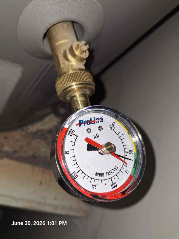 Responded to leak complaint with water penetrating ceiling from bathroom above. Upon inspection, identified active leak on corroded copper supply line beneath bathroom fixture. Copper piping exhibited significant verdigris corrosion at joint connection with visible water droplets present. Documented existing conditions including compromised pipe integrity and moisture damage. Verified system pressure at 0 PSI on gauge, indicating supply isolation. Assessed drainage assembly including P-trap and PVC connections for additional concerns. Photographed corroded copper line, pressure gauge readings, and affected plumbing components for documentation purposes.