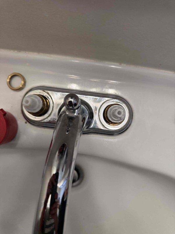 Responded to bathroom sink faucet leak. Upon inspection, identified corrosion and mineral deposits around mounting studs and connection points beneath the escutcheon plate. Removed existing faucet assembly using adjustable wrenches to access supply line connections and mounting hardware. Cleaned mounting surface and replaced corroded components to eliminate leak source and ensure proper seal at sink deck.