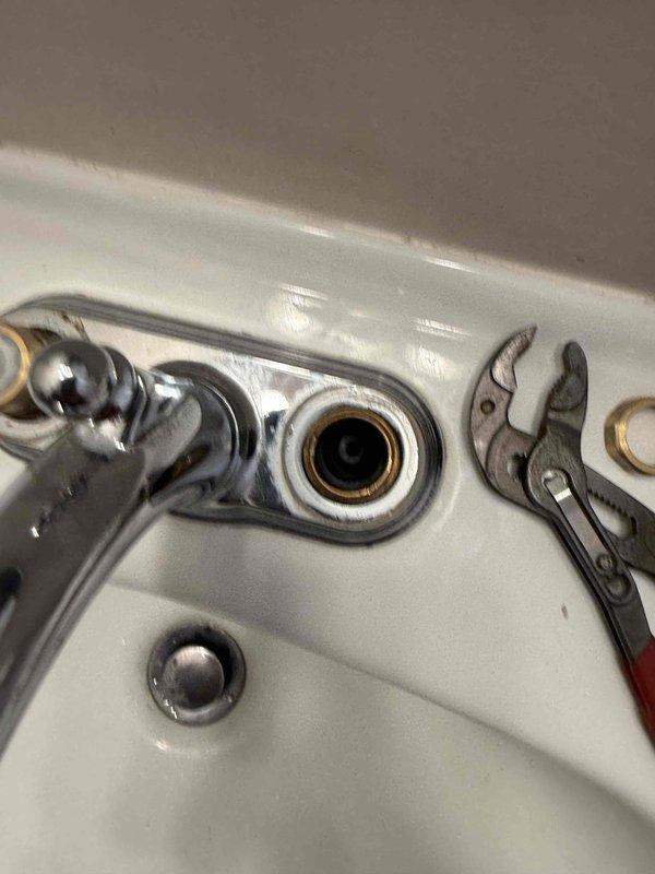 Responded to bathroom sink faucet leak. Upon inspection, identified corrosion and mineral deposits around mounting studs and connection points beneath the escutcheon plate. Removed existing faucet assembly using adjustable wrenches to access supply line connections and mounting hardware. Cleaned mounting surface and replaced corroded components to eliminate leak source and ensure proper seal at sink deck.