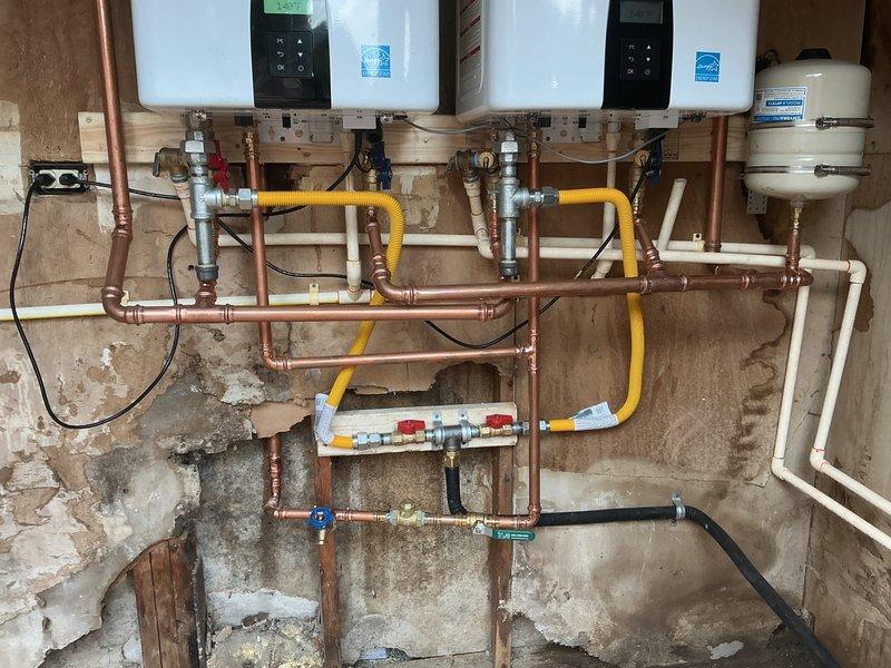 Replaced aging water heating system with dual tankless water heaters, including complete removal of deteriorated equipment and installation of new manifold distribution system with copper supply lines, yellow flexible gas connections, and white PVC venting. Installed expansion tank, upgraded plumbing connections with multiple shutoff valves, and ensured all components meet current code requirements for efficient on-demand hot water delivery. Replaced aging water heating system with dual tankless water heaters, including complete removal of deteriorated equipment and installation of new manifold distribution system with copper supply lines, yellow flexible gas connections, and white PVC venting. Installed expansion tank, upgraded plumbing connections with multiple shutoff valves, and ensured all components meet current code requirements for efficient on-demand hot water delivery.