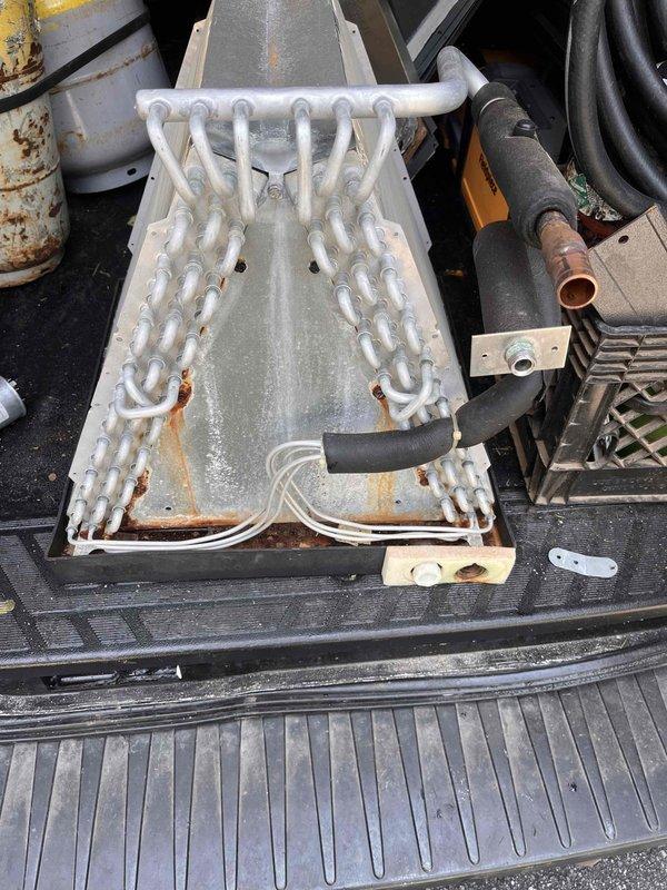 Replaced failed evaporator coil on Goodman furnace system in attic installation. Removed corroded coil assembly showing extensive rust damage at connection points and base, installed new coil unit, and reconnected refrigerant lines and ductwork to restore proper system operation.