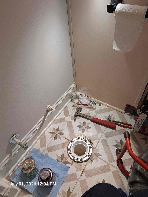 Responded to service call for two toilet flange issues and discolored water from rarely used bathtubs. Assessed existing toilet flange condition and discussed drilling out old flange for new installation, similar to previous toilet repair work completed at property. Removed toilet and evaluated flange mounting options for secure reinstallation. Addressed brown water concern in bathtubs, likely caused by sediment buildup and stagnant water in supply lines from infrequent use. Documented conditions with photos showing flange removal process, supply line configuration, and floor-mounted drain assembly with chrome hardware. Provided recommendations for flange replacement procedure and flushing protocol for affected bathtub fixtures to clear discolored water.