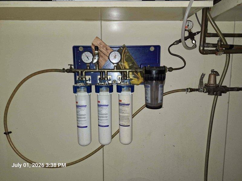 Responded to reported water leak causing elevated utility consumption at residential property. Upon inspection, identified active leak at whole-house water filtration system mounted in basement utility area. Leak originated from compromised o-ring seal on center filter housing, causing continuous water seepage. Shut off water supply, depressurized system, and replaced faulty o-ring seal. Reinstalled filter cartridge, verified proper seating, and restored water pressure. Conducted pressure test to confirm repair integrity with no further leakage detected. System returned to normal operation.