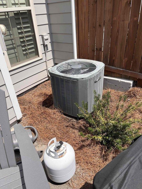 Responded to no cooling call on 11-year-old dual zone townhome system. Upon arrival, found cylindrical outdoor condensing unit with severe debris accumulation and lack of maintenance. Condenser coil heavily restricted with thick buildup of lint, fiber material, dust, and organic debris throughout fins and coil surfaces. Performed thorough coil cleaning to remove all contaminants and restore proper airflow through unit. Verified system operation and cooling performance after cleaning. Unit returned to normal operation with adequate airflow and refrigerant circuit function restored.
