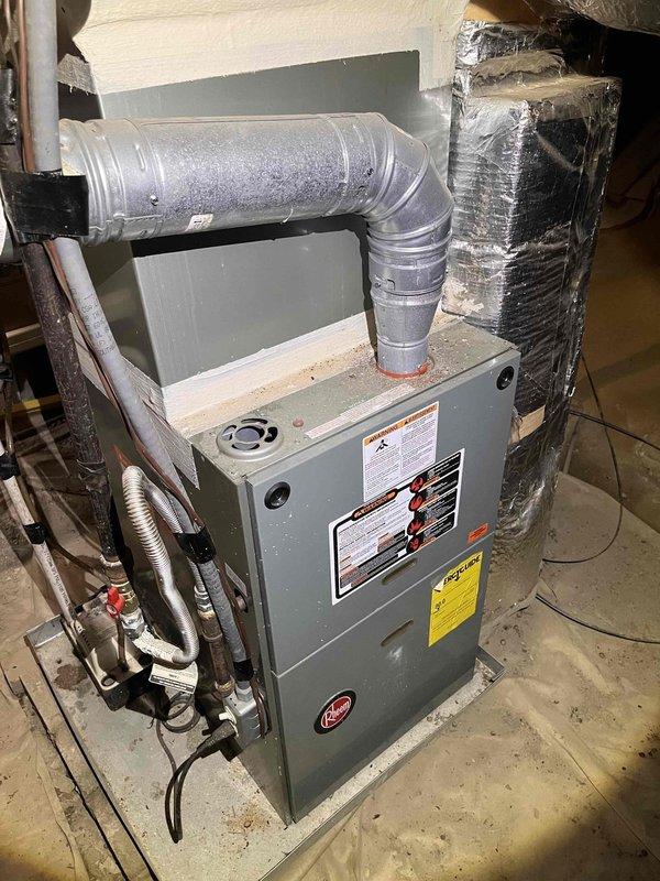 Responded to no cooling complaint with indoor temperature reaching 80 degrees. Inspected residential HVAC system including furnace unit and evaporator coil assembly. Found aged copper refrigerant lines showing significant oxidation and patina buildup, along with general dust accumulation on equipment. Airflow confirmed through vents but inadequate cooling performance observed. Documented existing equipment condition including ductwork connections, refrigerant line configuration, and overall system installation in basement mechanical room for further diagnostic evaluation and repair recommendations.