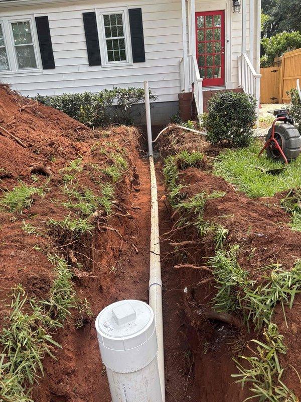 Completed full sewer line replacement at residential property. Excavated trench approximately 3-4 feet deep through lawn and landscaping beds, running parallel to house foundation through red clay soil. Removed existing deteriorated sewer line and installed new white PVC pipe from house connection to main sewer system. Installation included proper cleanout access point at base of trench for future maintenance needs. Backfilled excavated area upon completion of pipe installation and pressure testing. All work performed met local plumbing codes and specifications outlined in approved quote. Completed full sewer line replacement at residential property. Excavated trench approximately 3-4 feet deep through lawn and landscaping beds, running parallel to house foundation through red clay soil. Removed existing deteriorated sewer line and installed new white PVC pipe from house connection to main sewer system. Installation included proper cleanout access point at base of trench for future maintenance needs. Backfilled excavated area upon completion of pipe installation and pressure testing. All work performed met local plumbing codes and specifications outlined in approved quote.